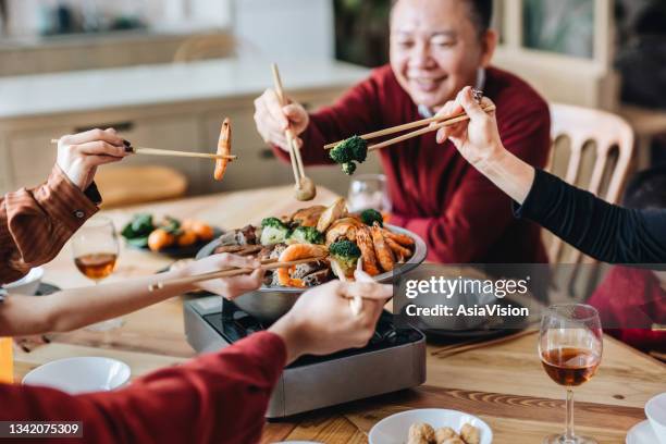 close up of three generations of joyful asian family celebrating chinese new year and enjoying scrumptious traditional chinese poon choi on reunion dinner - shared prosperity stock pictures, royalty-free photos & images