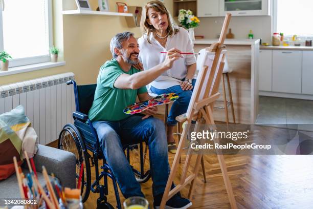 mature man in the wheelchair painting on a canvas in the living room - house for an art lover stock pictures, royalty-free photos & images