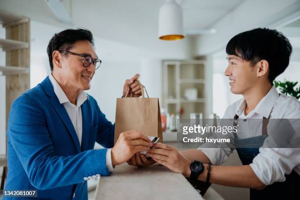 asian man using credit card contactless payment at cafe - happy cashier stock pictures, royalty-free photos & images