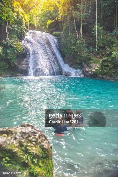 family swimming in secluded natural waterfall lagoon in tropical paradise - jamaican stock pictures, royalty-free photos & images