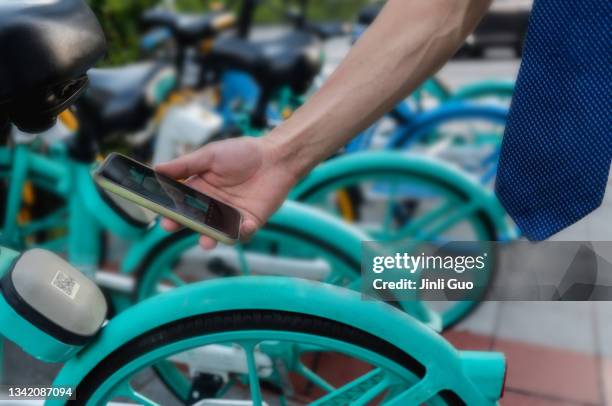 a man uses his smartphone to scan the qr code on the shared bicycle - kombinerad mobilitet bildbanksfoton och bilder