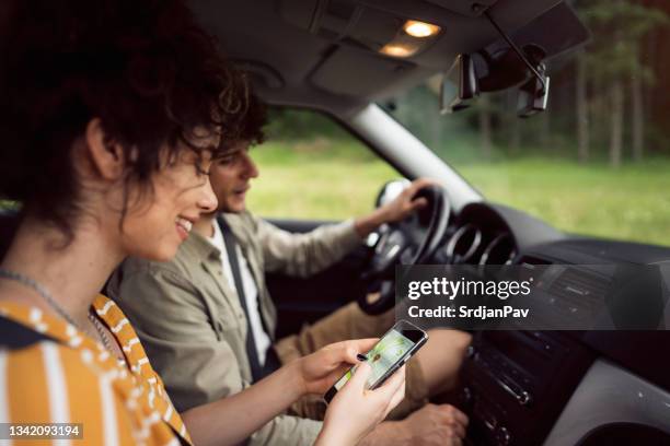 schönes junges paar, das mit dem smartphone auf einem roadtrip navigiert - auto navigation stock-fotos und bilder