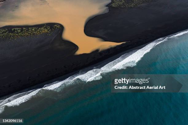 high angle perspective showing a black sand beach, the atlantic ocean and a vibrant coloured lake, iceland - black sand iceland stock pictures, royalty-free photos & images
