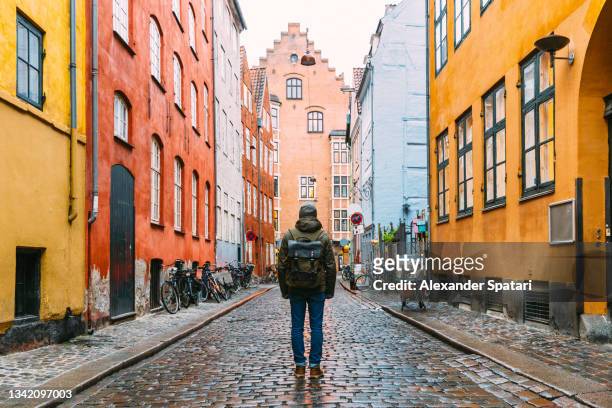 tourist with backpack exploring streets of copenhagen old town, denmark - copenhagen winter stock-fotos und bilder