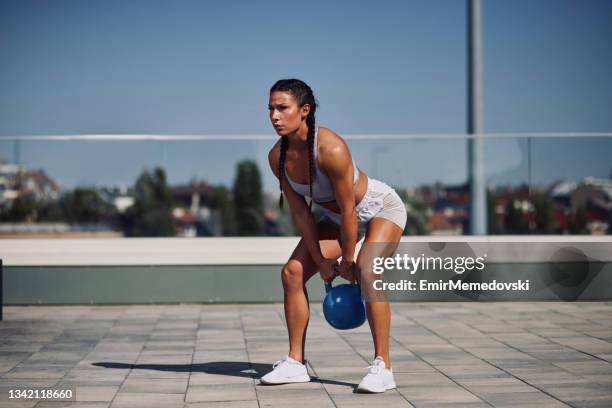 mujer joven haciendo ejercicio al aire libre con pesas de campana de hervidor - kettle bells fotografías e imágenes de stock