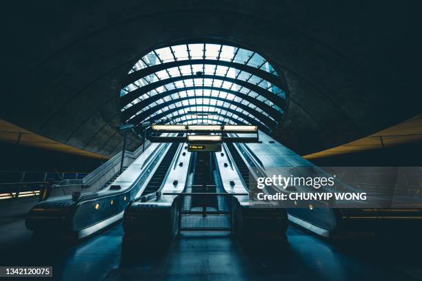 commuters on escalator at subway station canary wharf - crowded underground london stock pictures, royalty-free photos & images