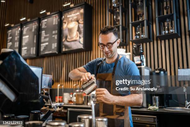 male barista making coffee for customers at the bar - barista coffee restaurant stockfoto's en -beelden