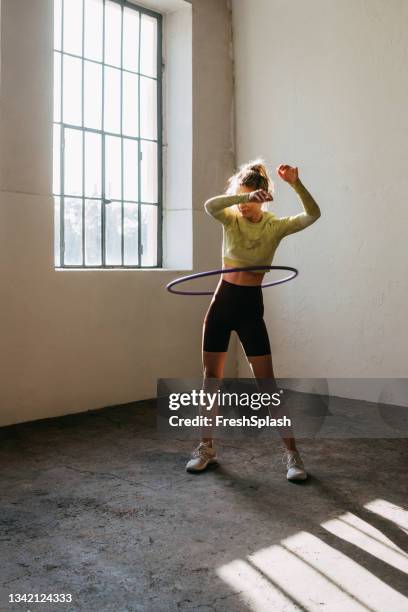 an anonymous fitness woman twirling hula hoop - hoelahoep stockfoto's en -beelden