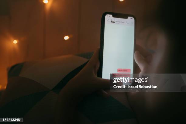 little girl using a mobile phone to send a text message with a christmas wish to santa claus. - children screen stock-fotos und bilder