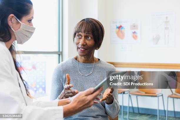 senior female patient asks doctor about test results - mid adult patient stock pictures, royalty-free photos & images