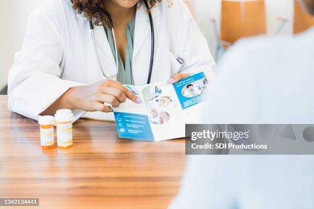 unrecognizable doctor discusses care options with patient - brochure stockfoto's en -beelden