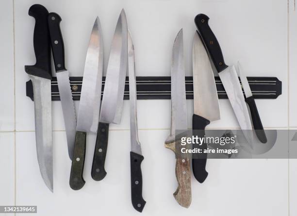 close-up of top view of set of knives of kitchen metal displayed on magnetic holder on the kitchen white counter - tafelmes stockfoto's en -beelden