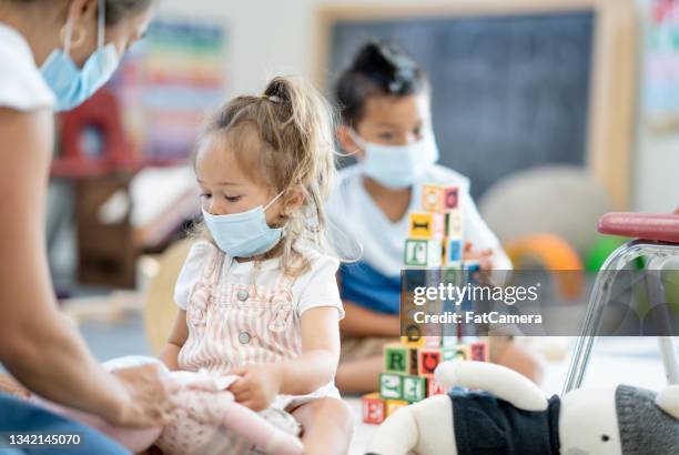 little girl playing with her doll in a preschool class - infectious disease child stock pictures, royalty-free photos & images