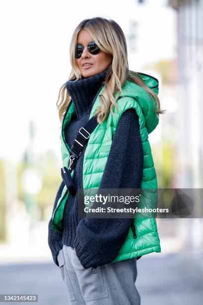 Influencer Gitta Banko wearing a dark blue oversized knitted turtleneck pullover with silver glitter by Antonia Zander, a light green vest by...