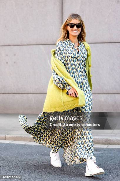 Influencer Gitta Banko wearing a multicolored longsleeve maxi dress with abstract pattern by Odeeh, a yellow knitted cardigan without sleeves by...