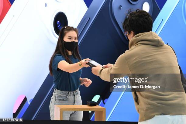 Jun Matsuda receives his newly purchased iPhone Pro from an Apple Store staff member inside the Apple Store on George Street on September 24, 2021 in...