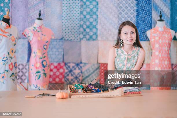 malaysian chinese beautiful  woman boutique small business owner portrait in front of her batik cheongsam fabric textile collection retail store looking at camera smiling - malaysia batik stock pictures, royalty-free photos & images