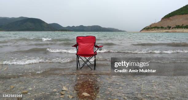 empty red camping chair inside the lake water. - chaise de dos photos et images de collection