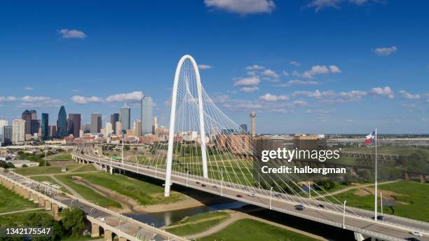 drohnenaufnahme der texanischen staatsflagge, die über die margaret hunt hill bridge mit der skyline von dallas weht - texas flag stock-fotos und bilder