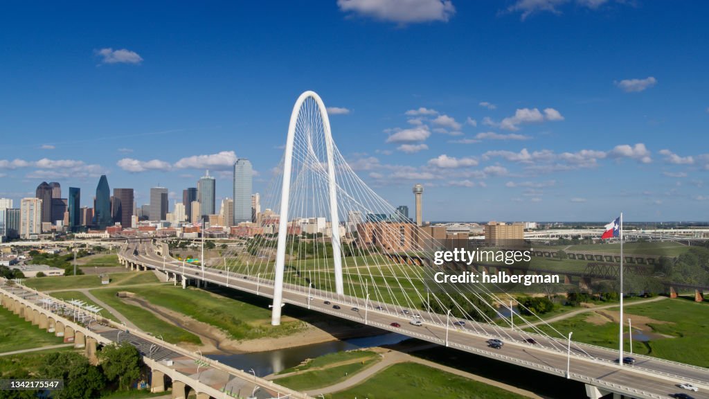 Drone Shot da Bandeira do Estado do Texas acenando sobre a ponte Margaret Hunt Hill com o Horizonte de Dallas