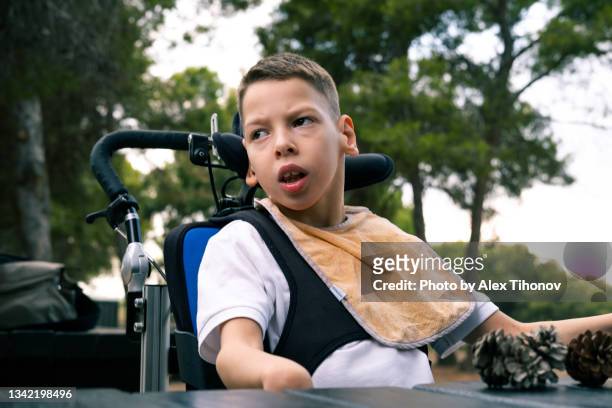 little 9s boy with cerebral palsy sit in wheelchair outdoor - motorized wheelchair stock pictures, royalty-free photos & images