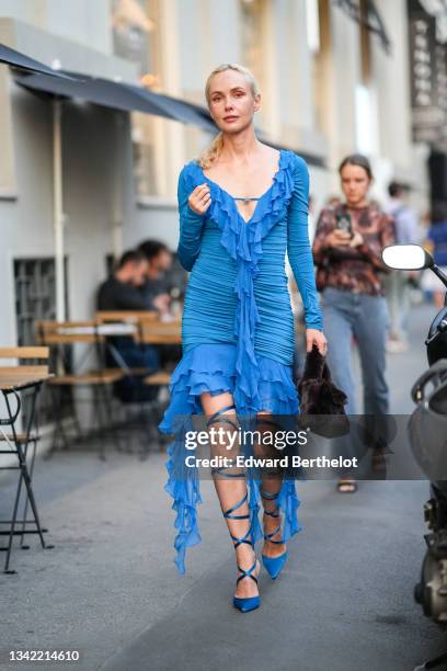 Olga Karput wears a blue ruffled V-neck / long sleeves / asymmetric short dress with long ruffled strap, blue shiny satin pointed pumps heels shoes...