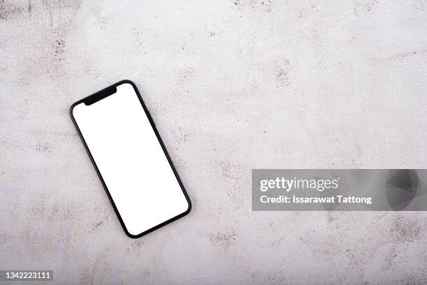 mobile phone with empty screen on black desktop. top view - oberteil stock-fotos und bilder