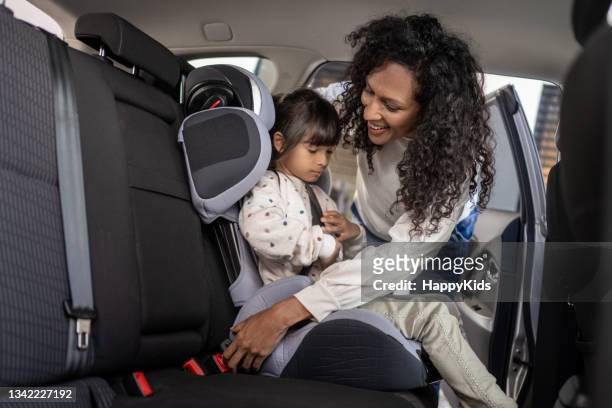 mujer abrochándose el cinturón de seguridad de su hija - abrochar fotografías e imágenes de stock