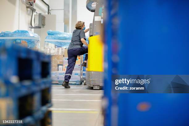 arbeiter, der im lager auf gabelstapler umsteigen - automatisiertes fahren stock-fotos und bilder