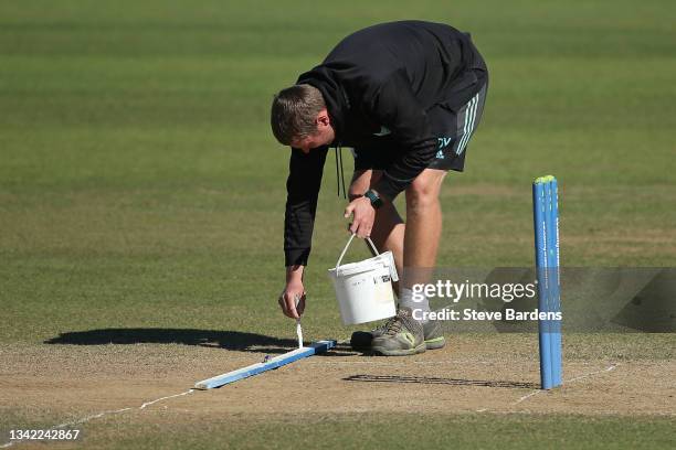 Member of the Surrey ground staff repaints the crease line on the wicket on day four during the LV= Insurance County Championship match between...