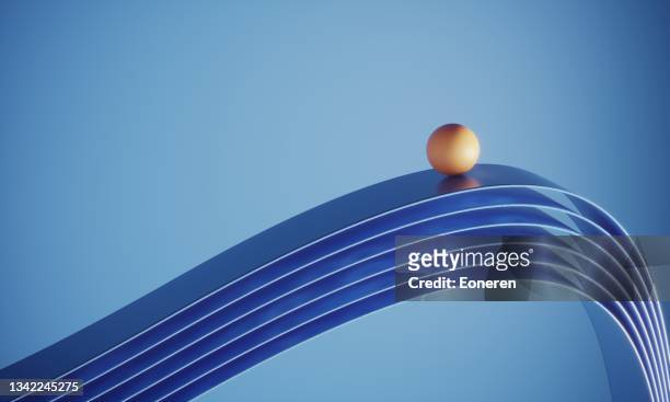 orange colored ball standing on top of the ribbons - business balance stock pictures, royalty-free photos & images