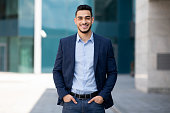 Handsome middle-eastern guy businessman posing next to office center