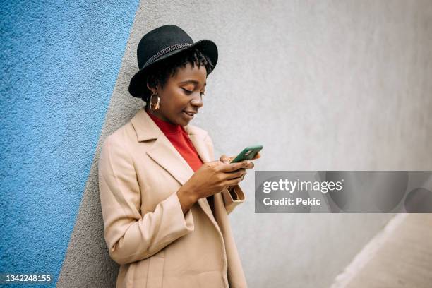 young casually clothed woman using smartphone - blue coat stock pictures, royalty-free photos & images