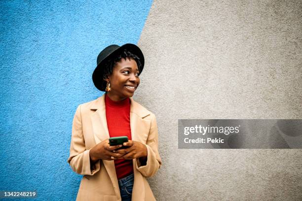 joven vestida casualmente posando frente a una pared de colores - abrigo azul fotografías e imágenes de stock