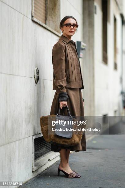 Mary Leest wears black transparent shirt, a brown shirt jacket, a brown matching long flowing skirt, a black leather and brown fluffy large handbag...