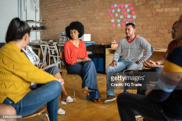 young woman talking in group therapy at a coworking - including a transgender person - focus group discussion stock pictures, royalty-free photos & images
