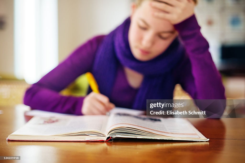 Girl sitting at table and doing her homework