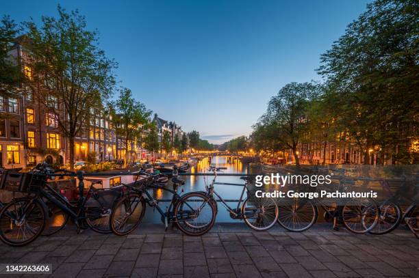 bicycles on a bridge in amsterdam at dusk - amstel stockfoto's en -beelden