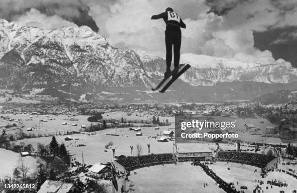 An unspecified ski-jumper competes against a backdrop of the Wetterstein Mountains at the 1936 Winter Olympics, held in Garmisch-Partenkirchen,...