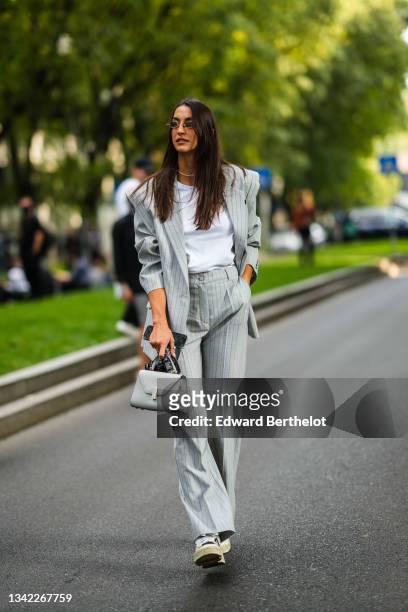 Guest wears sunglasses, a white t-shirt, necklaces, a pale gray with blue small stripes oversized epaulets blazer jacket, pale gray with blue small...