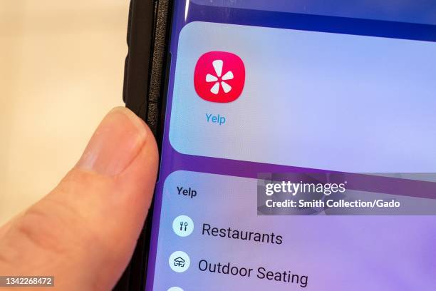 Close-up of human hand holding a cellphone displaying icon for the Yelp ratings app, Lafayette, California, September 22, 2021.