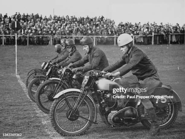 Five unspecified riders at the starting line of a motorcycle race, location unspecified, 1938. Spectators are visible in the background.