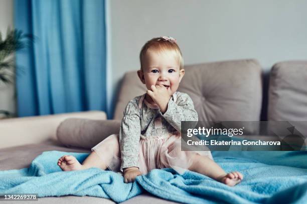 a beautiful little girl of 1 year old is sitting on the sofa - baby clothes bildbanksfoton och bilder