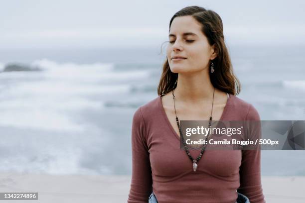 young woman enjoying a meditative moment by the sea - mental toughness stock pictures, royalty-free photos & images