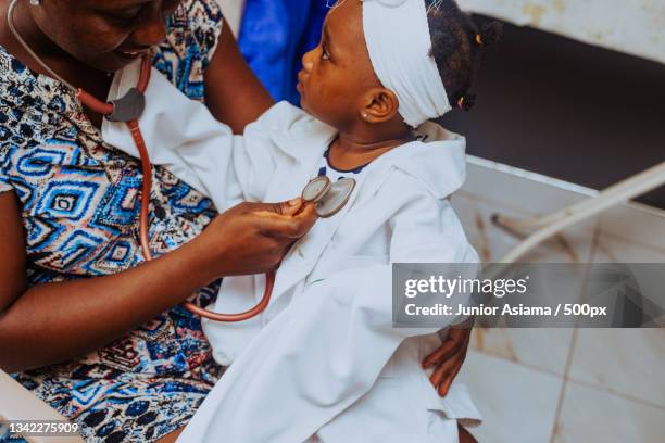 mother playing doctor with her young daughter,accra,ghana - ghanaian family stock-fotos und bilder