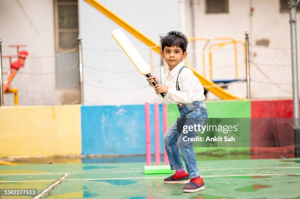 süßes indisches kleines kind, das cricket auf dem spielplatz spielt. - cricketer stock-fotos und bilder