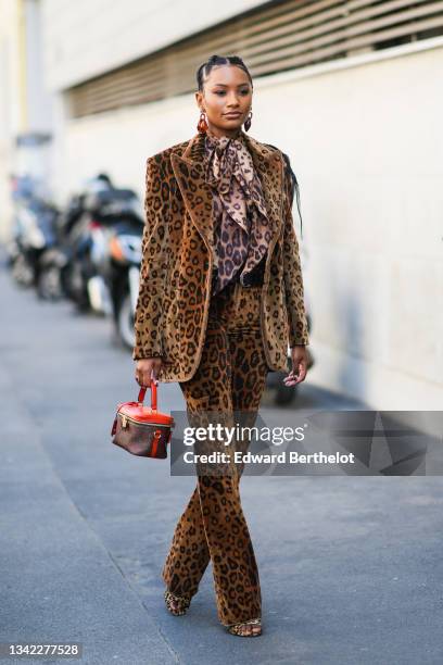 Guest wears brown large earrings, a black and brown leopard print pattern knotted shirt, a black and brown leopard print pattern velvet blazer...