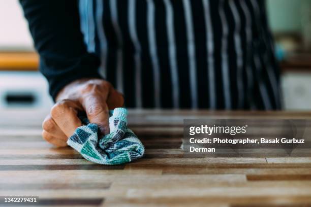 close-up of man's hand cleaning the surface of a table with a cleaning cloth at home - spültuch stock-fotos und bilder