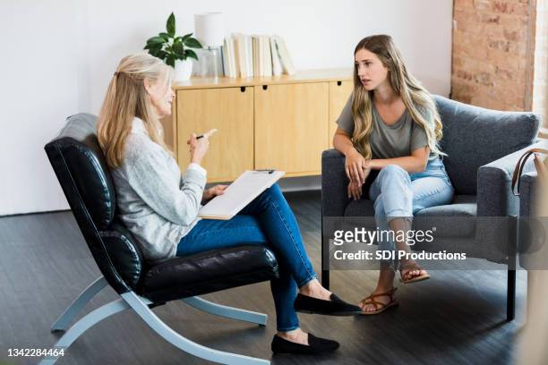 mature therapist shakes finger and lectures young female client - psychotherapy imagens e fotografias de stock