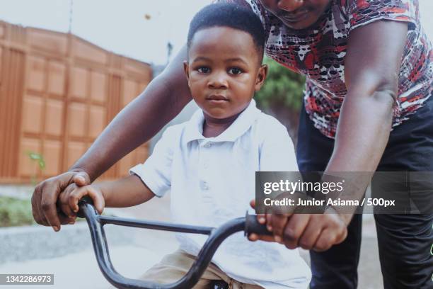 high angle view of father teaching his little boy to ride a bike,tema,ghana - ghanaian family stock pictures, royalty-free photos & images